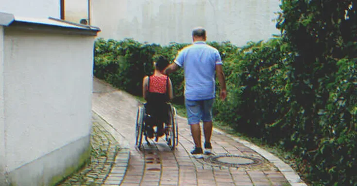 A girl in a wheelchair next to a man | Source: Shutterstock