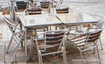 Metal tables and chairs on the pavement outside a cafe. | Source: Getty Images