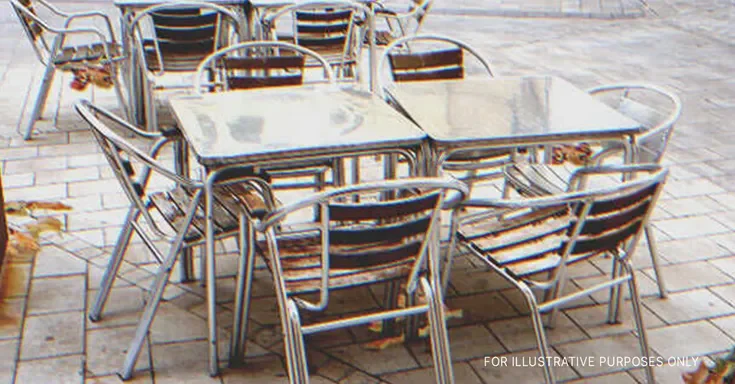 Metal tables and chairs on the pavement outside a cafe. | Source: Getty Images