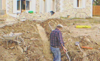 A man digging on the ground next to a house | Source: Shutterstock