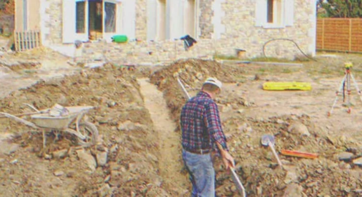 A man digging on the ground next to a house | Source: Shutterstock