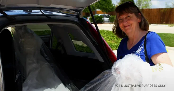 An elderly woman taking out a bridal dress from her car's trunk | Source: Flickr/waitscm/CC BY 2.0