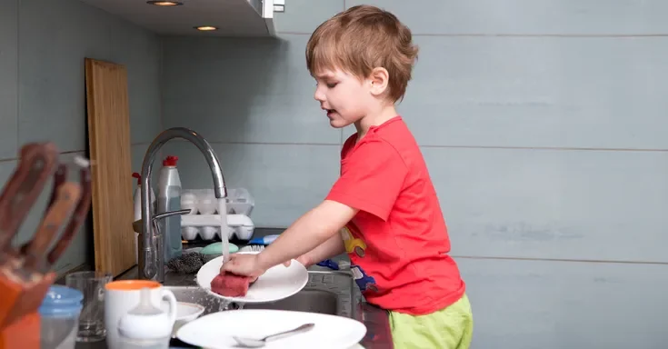 A boy washing dishes | Source: Shutterstock