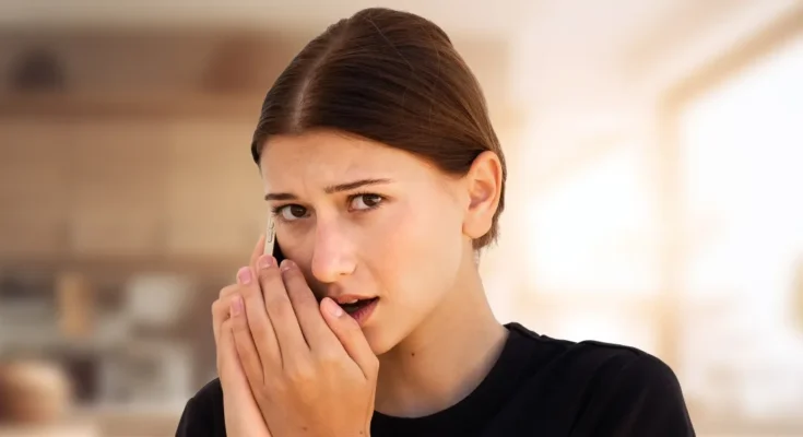 A young woman speaking secretively on her phone | Source: Shutterstock