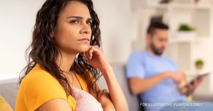 A serious woman lost in her thoughts while sitting next to her partner | Source: Shutterstock