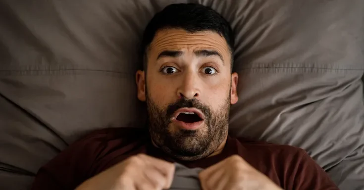 A shocked man in bed | Source: Shutterstock