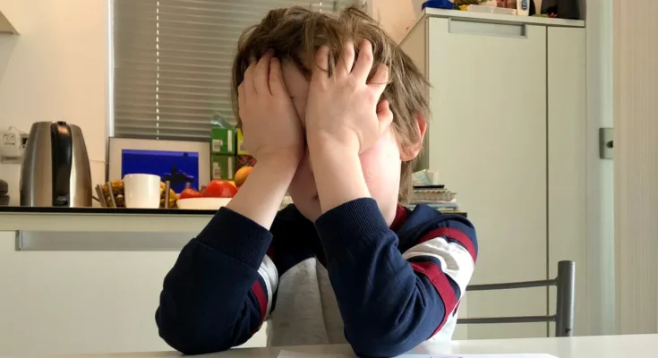 A boy covering his face with his hands | Source: Shutterstock