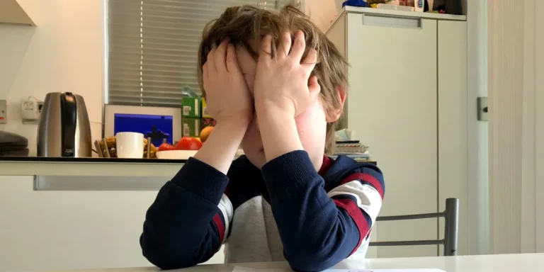 A boy covering his face with his hands | Source: Shutterstock