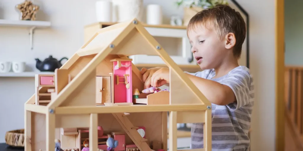 A boy playing with a dollhouse | Source: Shutterstock