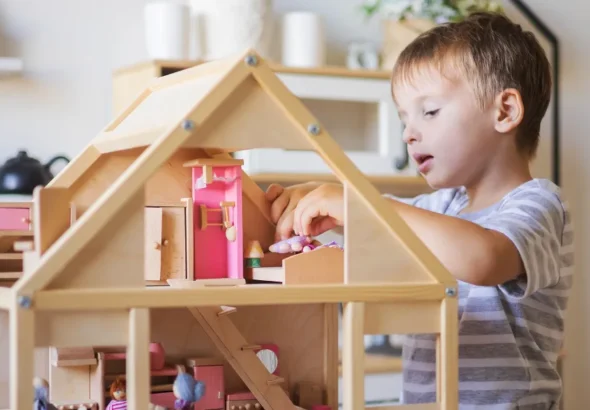 A boy playing with a dollhouse | Source: Shutterstock