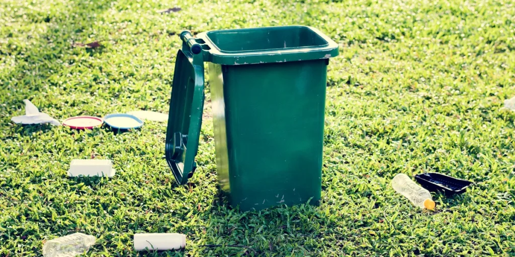 A bin and trash on a lawn | Source: Shutterstock