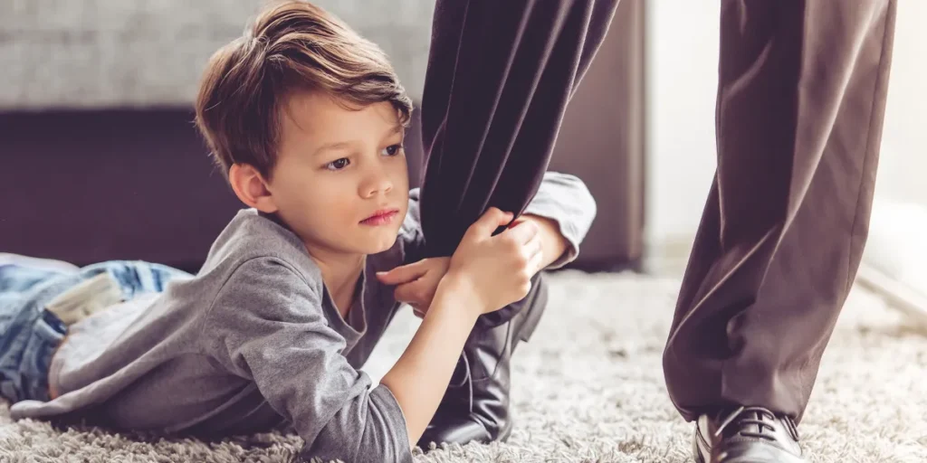 A kid holding onto an adult's leg | Source: Shutterstock