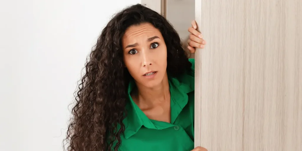 Woman with a shocked expression opening her front door | Source: Shutterstock