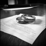 Divorce paperwork and rings on a table | Source: Midjourney