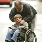 A homeless man leaning over a smiling boy in a wheelchair | Source: Amomama